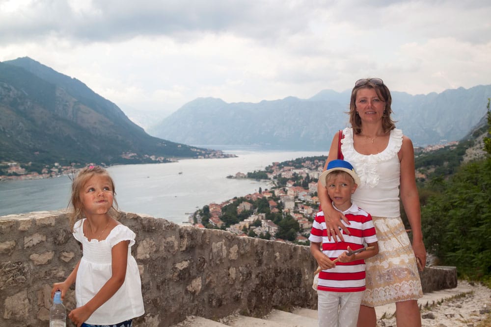 Жінка з двома дітьми на оглядовому майданчику з видом на гірську затоку та місто