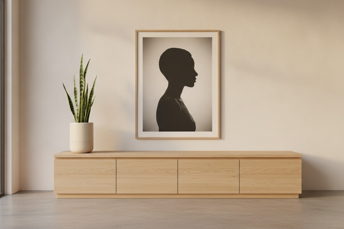 Ein einzelnes gerahmtes Schwarz-Weiß-Porträt hängt mit viel Freiraum über einem hellen Sideboard.