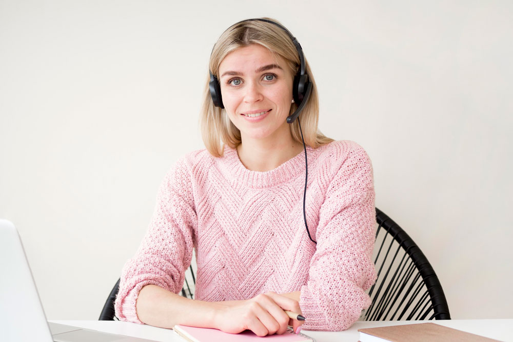 Репетитор проводить онлайн-урок у навушниках із мікрофоном, працює з учнем через ноутбук.