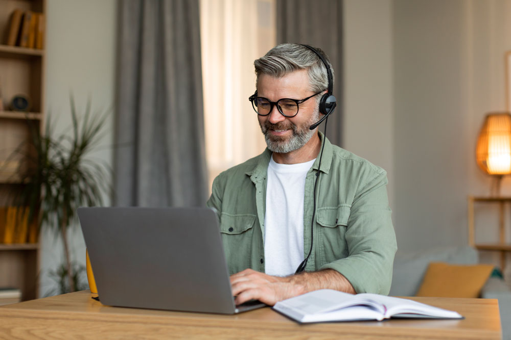 Чоловік бере участь в онлайн-уроці з гарнітурою за ноутбуком